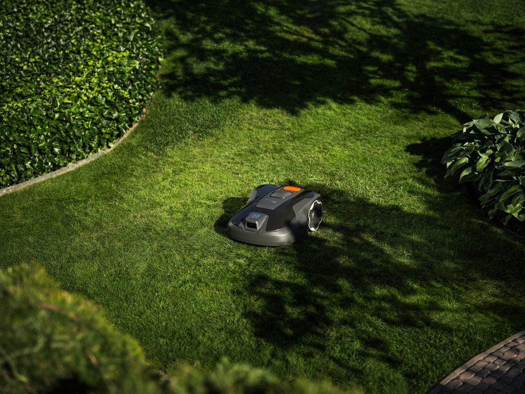 Husqvarna Automower 312V smart robotic mower cutting grass in a medium-sized suburban backyard, supplied by Grafton Power Products.