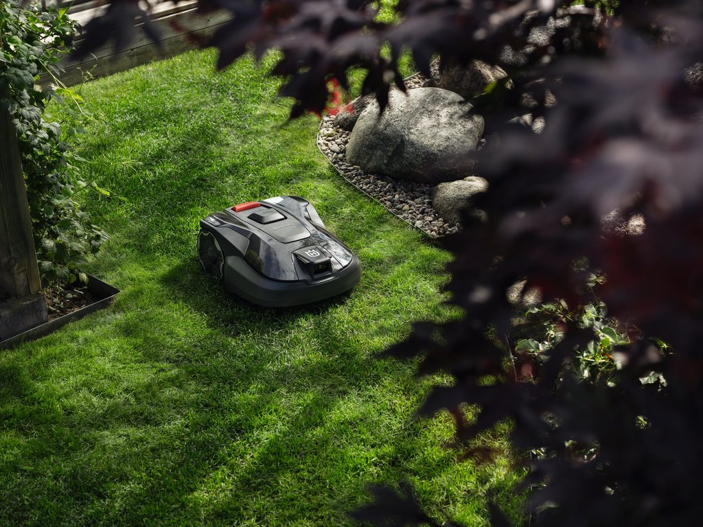 Husqvarna Automower 312V smart robotic mower cutting grass in a medium-sized suburban backyard, supplied by Grafton Power Products.